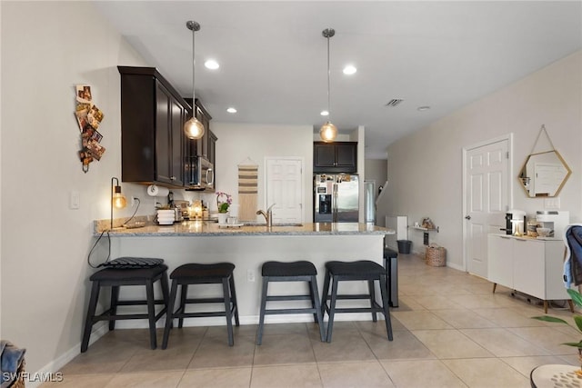 kitchen with pendant lighting, stainless steel appliances, kitchen peninsula, and light stone counters