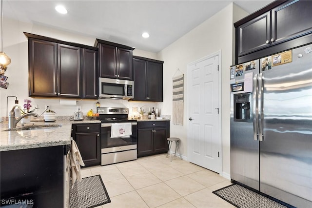 kitchen with light tile patterned flooring, sink, dark brown cabinets, stainless steel appliances, and light stone countertops