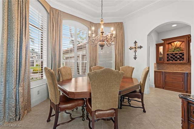 dining room featuring crown molding, a wealth of natural light, a raised ceiling, and light tile patterned flooring