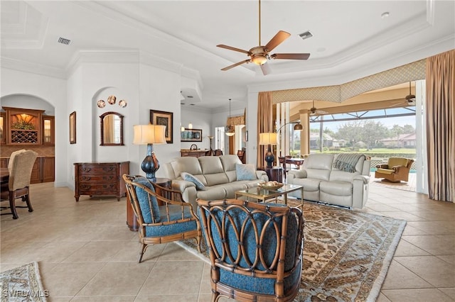 living room with light tile patterned floors, a tray ceiling, ornamental molding, and ceiling fan