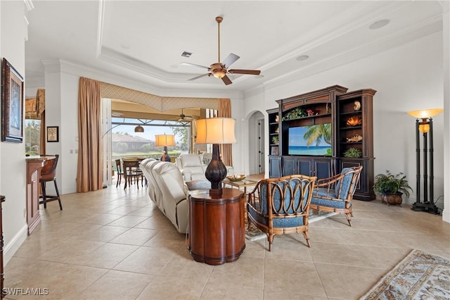 tiled living room featuring a tray ceiling, ornamental molding, and ceiling fan