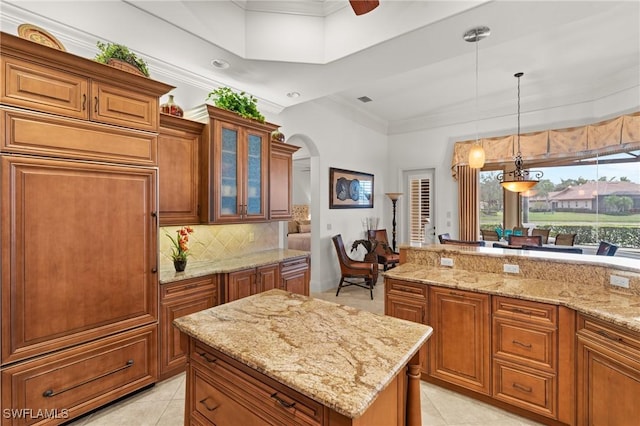 kitchen with pendant lighting, light tile patterned floors, a center island, light stone counters, and tasteful backsplash