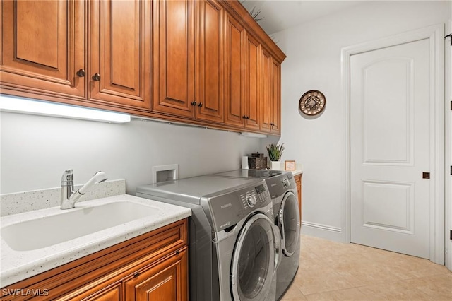 washroom with cabinets, sink, washing machine and dryer, and light tile patterned floors