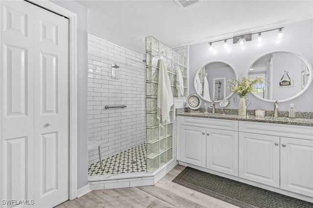 bathroom featuring vanity, hardwood / wood-style floors, and a tile shower