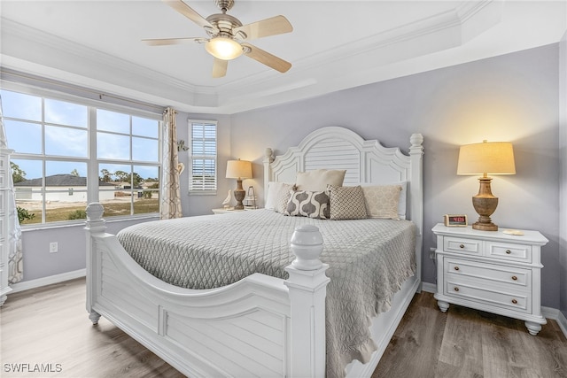 bedroom featuring ceiling fan, dark wood-type flooring, a tray ceiling, and crown molding