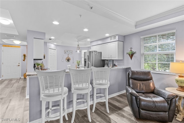 kitchen with stainless steel fridge, white cabinets, kitchen peninsula, ornamental molding, and a tray ceiling