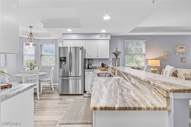 kitchen with stainless steel refrigerator with ice dispenser, sink, white cabinets, and a tray ceiling