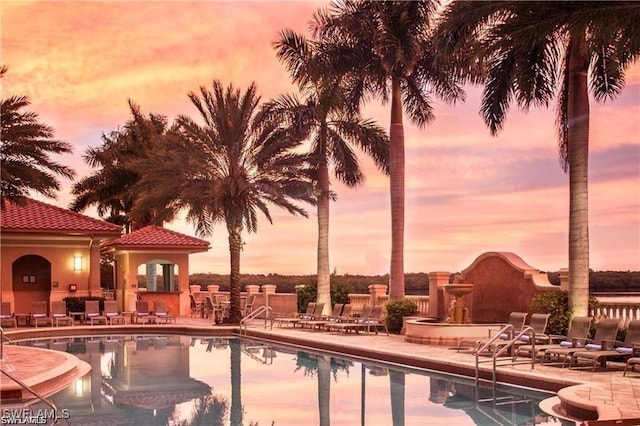 pool at dusk featuring a patio area