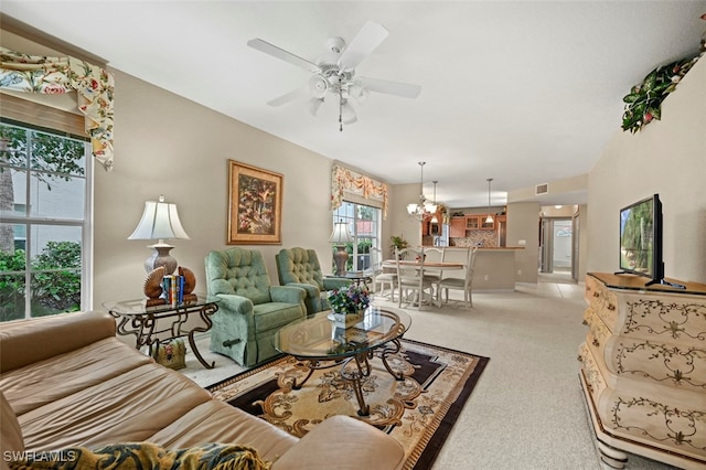 living room featuring ceiling fan with notable chandelier and light colored carpet