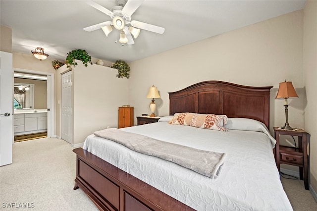 bedroom with ceiling fan, light colored carpet, and ensuite bath