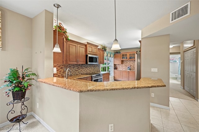 kitchen featuring pendant lighting, light stone counters, stainless steel appliances, and kitchen peninsula