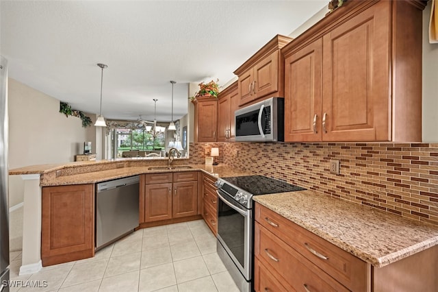 kitchen featuring sink, light stone counters, decorative light fixtures, kitchen peninsula, and stainless steel appliances