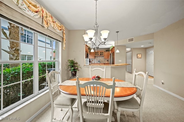 carpeted dining space featuring plenty of natural light and a chandelier