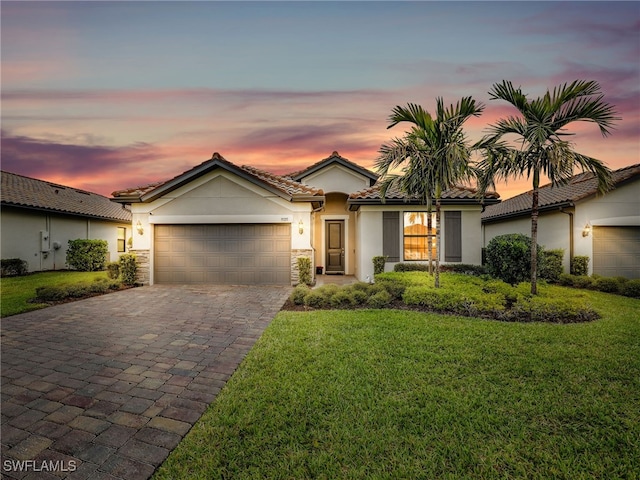 view of front of home with a tile roof, a front yard, stucco siding, decorative driveway, and a garage