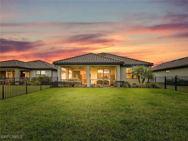 back house at dusk with a lawn