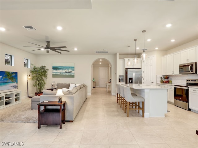 kitchen featuring a breakfast bar, white cabinetry, an island with sink, pendant lighting, and stainless steel appliances