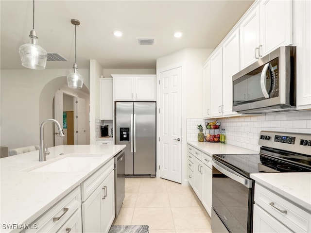 kitchen with appliances with stainless steel finishes, sink, hanging light fixtures, and white cabinets