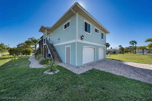 back of house with a garage and a lawn