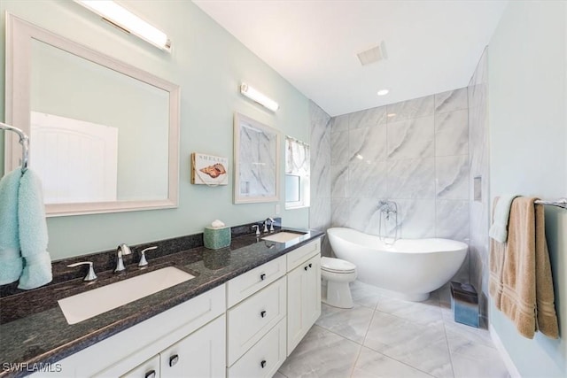 bathroom featuring vanity, a bathtub, tile walls, and toilet