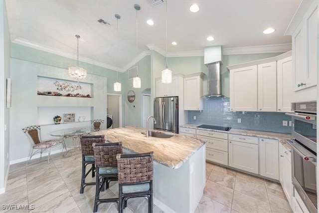 kitchen featuring white cabinets, stainless steel appliances, an island with sink, a kitchen breakfast bar, and hanging light fixtures