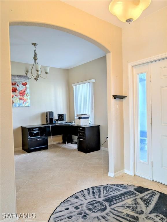 entrance foyer featuring arched walkways, light tile patterned floors, baseboards, and an inviting chandelier