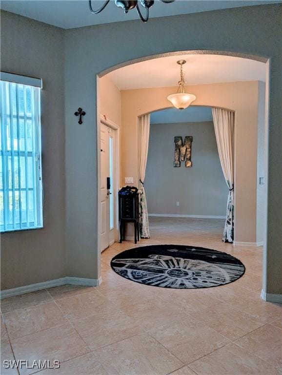 tiled entryway featuring baseboards and arched walkways