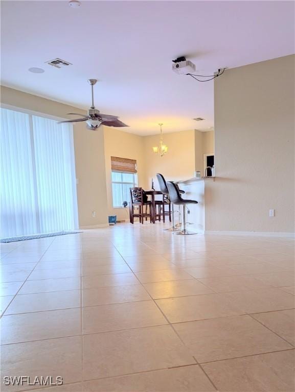 tiled empty room with ceiling fan, visible vents, and baseboards