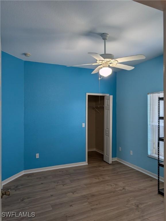 unfurnished bedroom featuring ceiling fan, a closet, baseboards, and wood finished floors