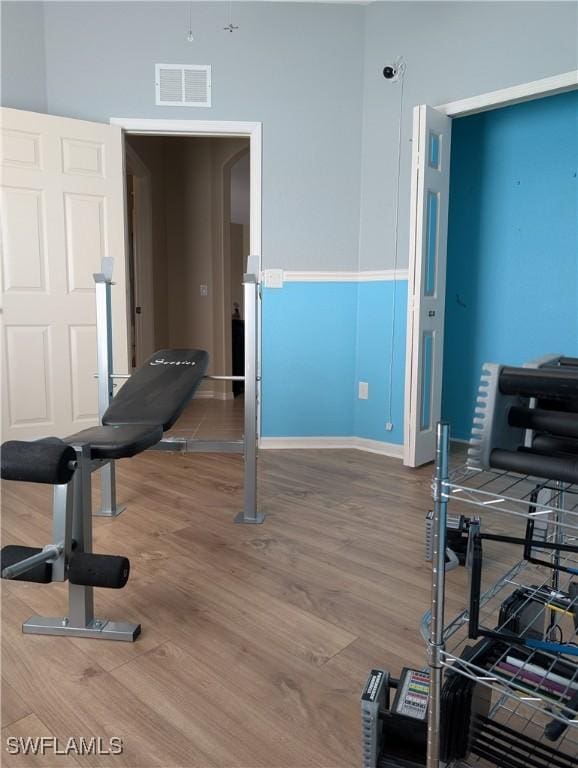 exercise room with visible vents, baseboards, and wood finished floors