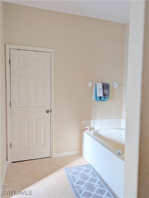 bathroom featuring tile patterned flooring, baseboards, and a bath