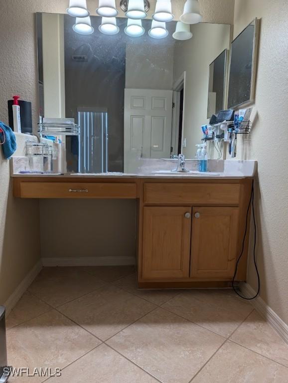 bathroom with a textured wall, tile patterned flooring, baseboards, and vanity