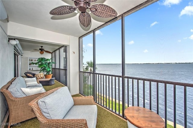 sunroom with ceiling fan and a water view