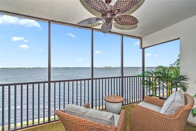 sunroom featuring ceiling fan and a water view