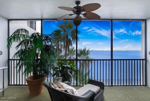 sunroom featuring ceiling fan and a water view