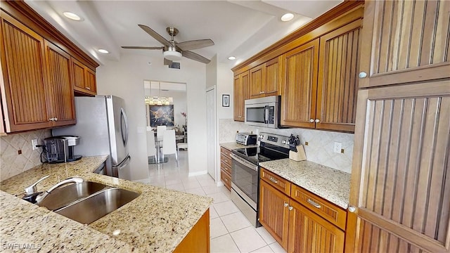 kitchen with tasteful backsplash, light stone countertops, appliances with stainless steel finishes, and sink