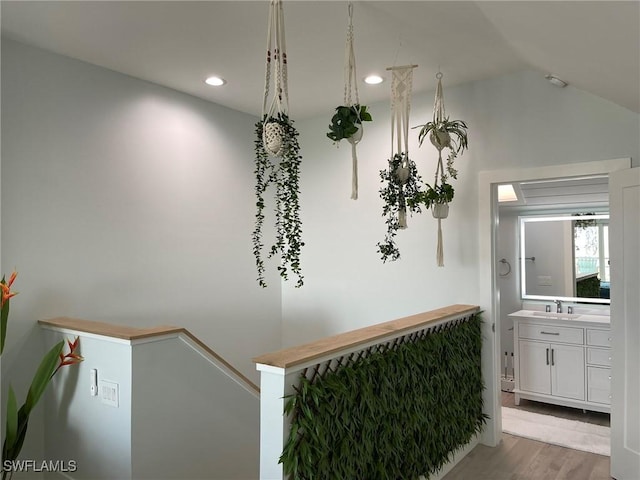 hallway with vaulted ceiling, sink, and light hardwood / wood-style flooring