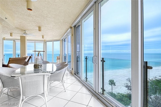 sunroom / solarium featuring a water view and ceiling fan