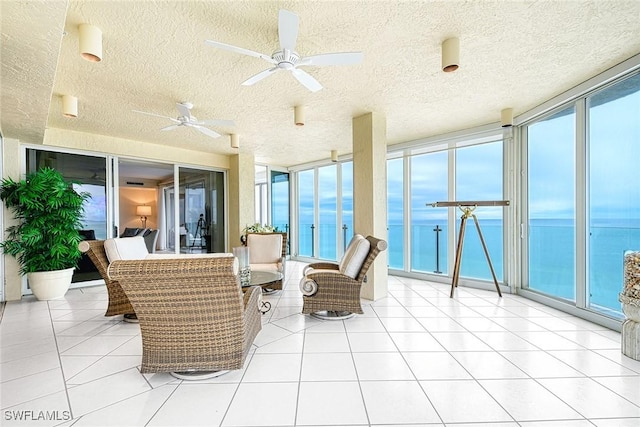 sunroom / solarium with ceiling fan and a water view