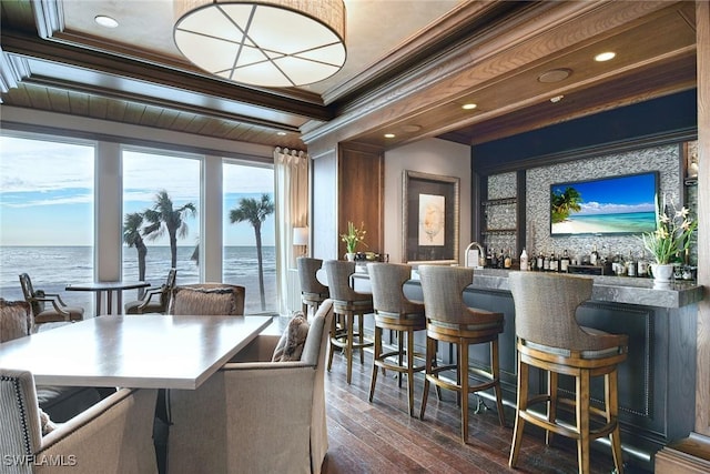 interior space with dark wood-type flooring, ornamental molding, and a water view