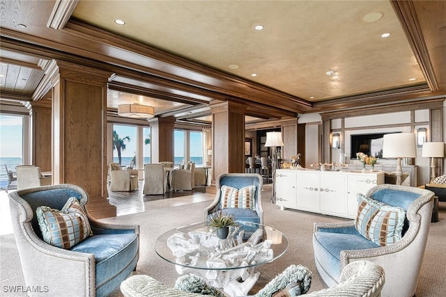 carpeted living room featuring ornate columns, crown molding, and a water view