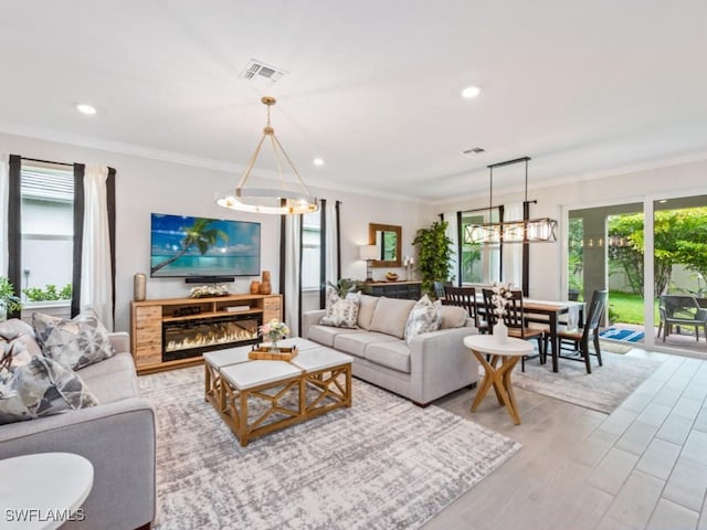 living room with crown molding, a wealth of natural light, and light hardwood / wood-style floors