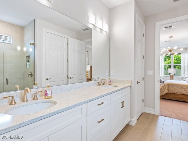 bathroom with an inviting chandelier, vanity, a shower with shower door, and hardwood / wood-style flooring