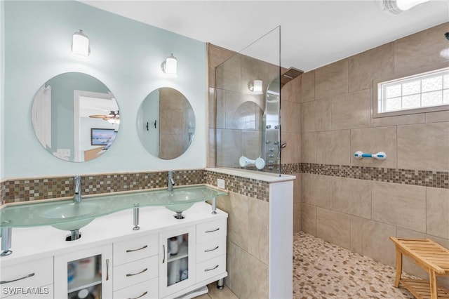 bathroom featuring tiled shower, vanity, and tile walls