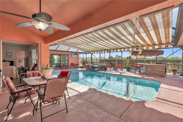 view of swimming pool featuring glass enclosure, ceiling fan, and a patio area