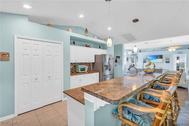 kitchen featuring a kitchen bar, white cabinetry, stainless steel fridge with ice dispenser, hanging light fixtures, and a kitchen island