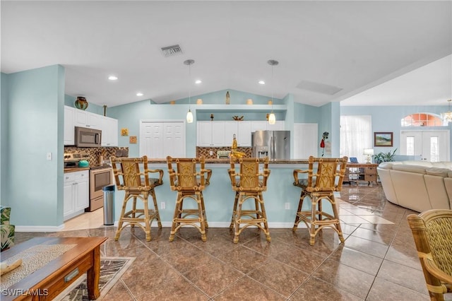 kitchen with white cabinetry, appliances with stainless steel finishes, and a breakfast bar area