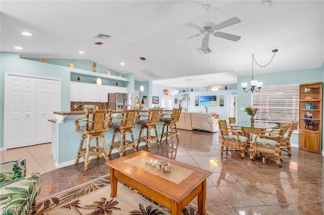 tiled living room featuring lofted ceiling and ceiling fan with notable chandelier