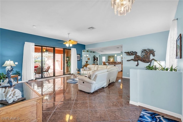 living room with ceiling fan with notable chandelier and dark tile patterned floors