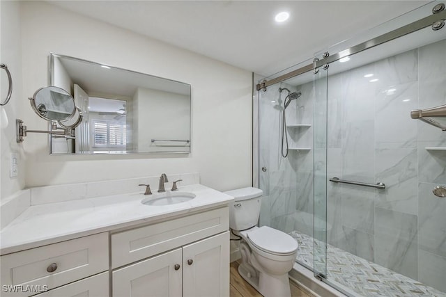 bathroom with vanity, hardwood / wood-style flooring, a shower with shower door, and toilet