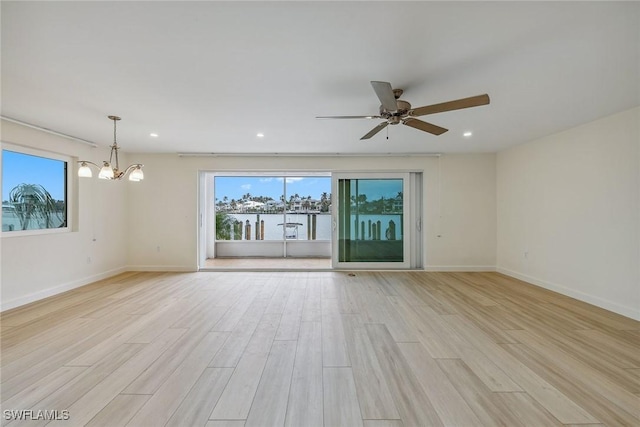 unfurnished room with ceiling fan with notable chandelier and light wood-type flooring